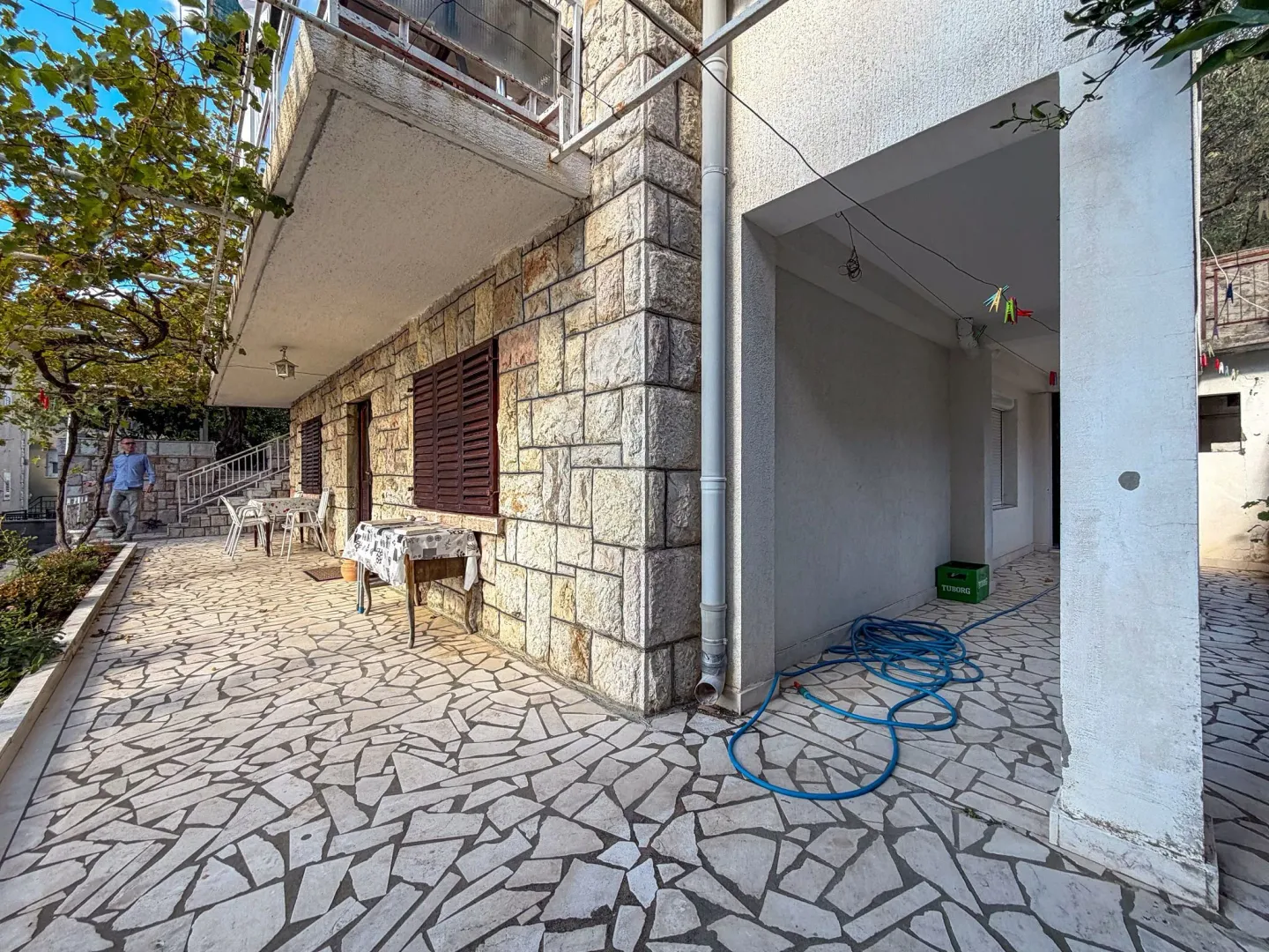 Dvorište sa kamenom fasadom i terasom ispred kuće.
