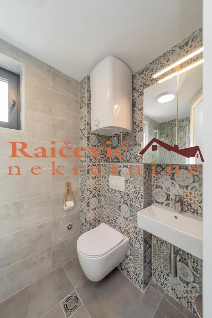 Compact bathroom with a shower, sink, toilet, and water heater.