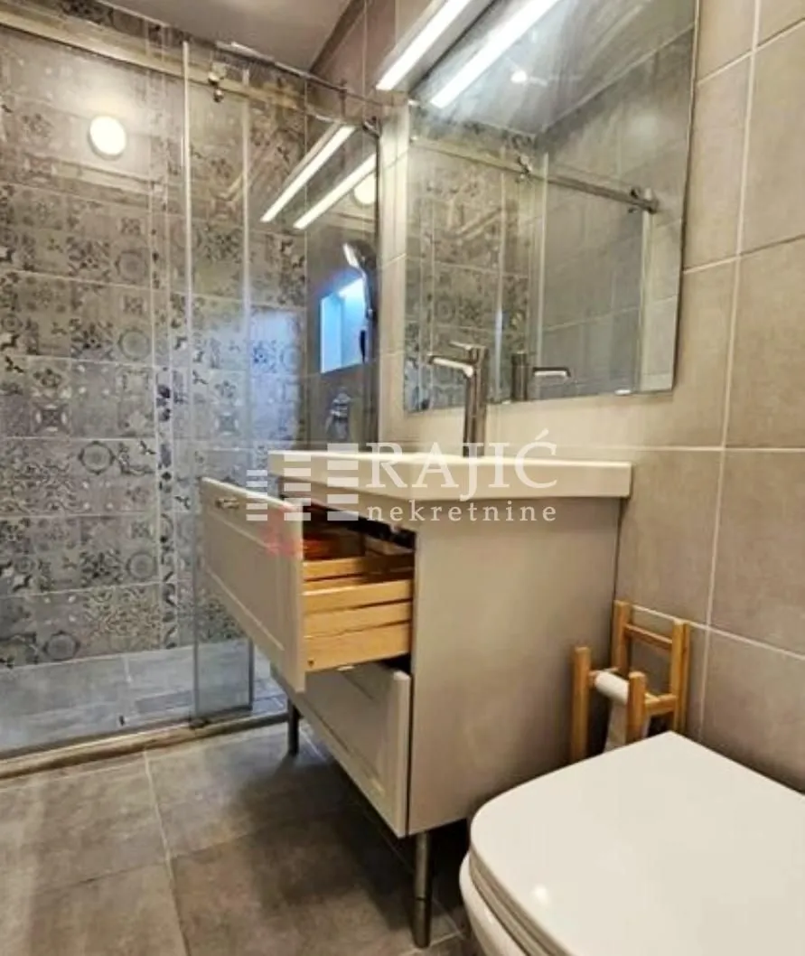 Modern equipped bathroom with a washbasin and walk-in shower.
