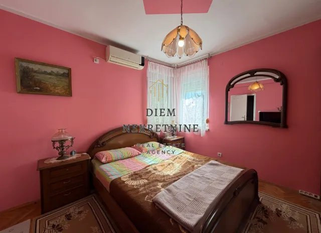 Bedroom with a double bed, pink walls, and wooden furniture.