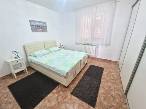 Namještena spavaća soba sa bračnim krevetom, bijelim noćnim stočićima i velikim ormarom. - image 6