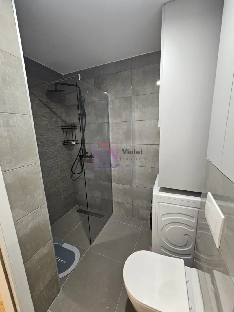 Modernly equipped bathroom with a walk-in shower and washing machine.