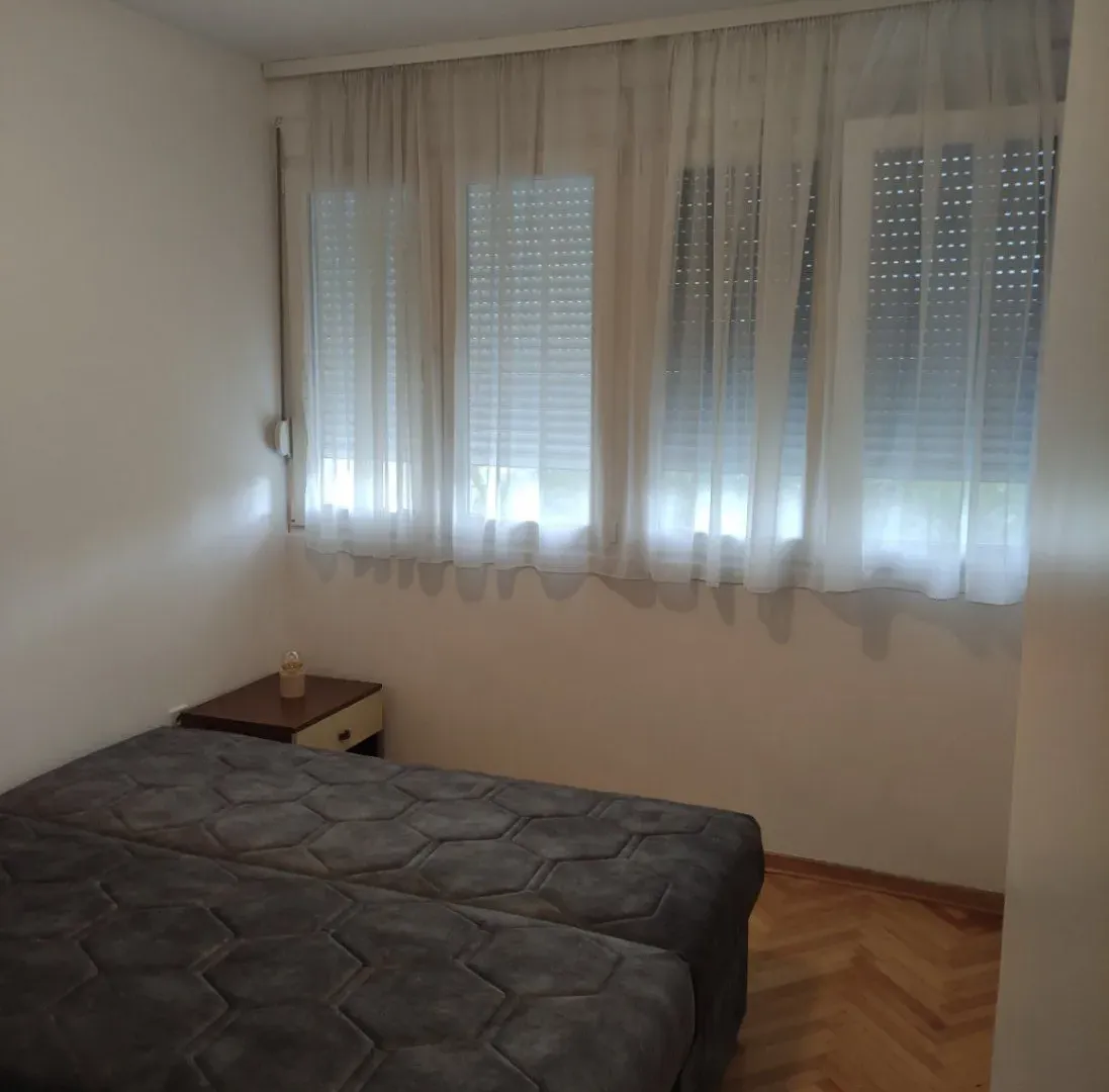 Spavaća soba sa krevetom i prozorima prekrivenim zavjesama.