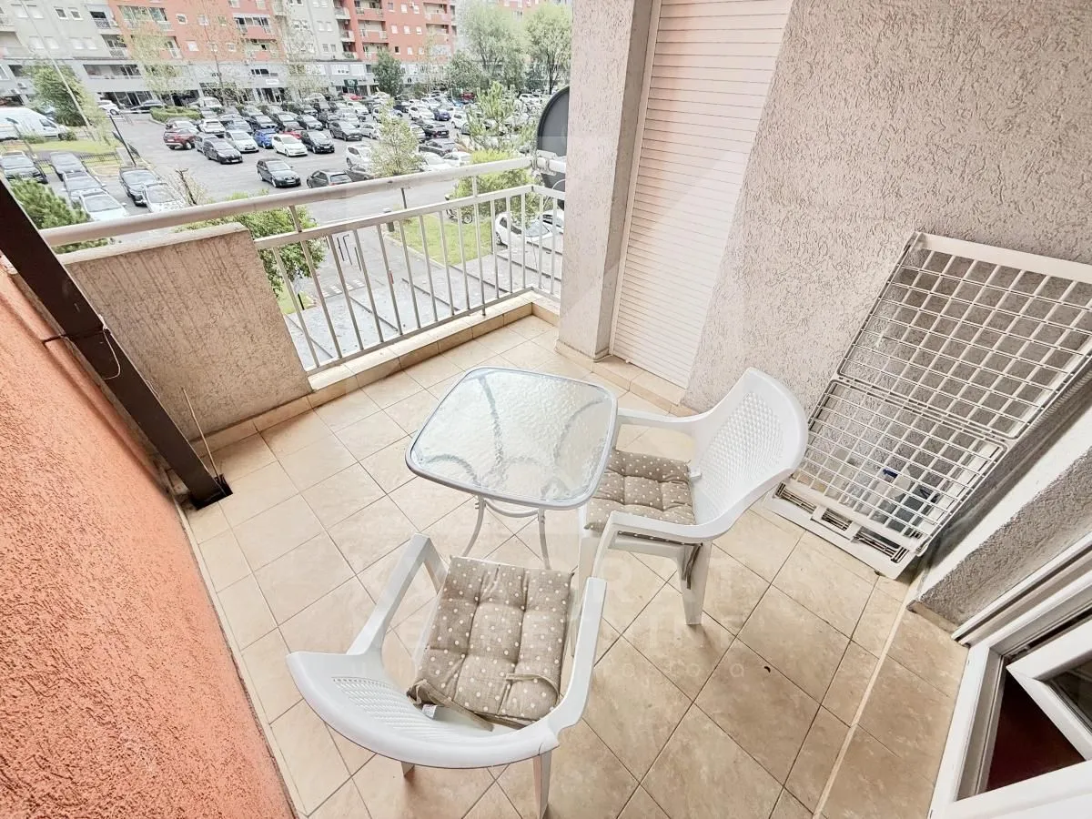 Namtješten balkon sa stočićem i dvije stolice, sa pogledom na ulicu.