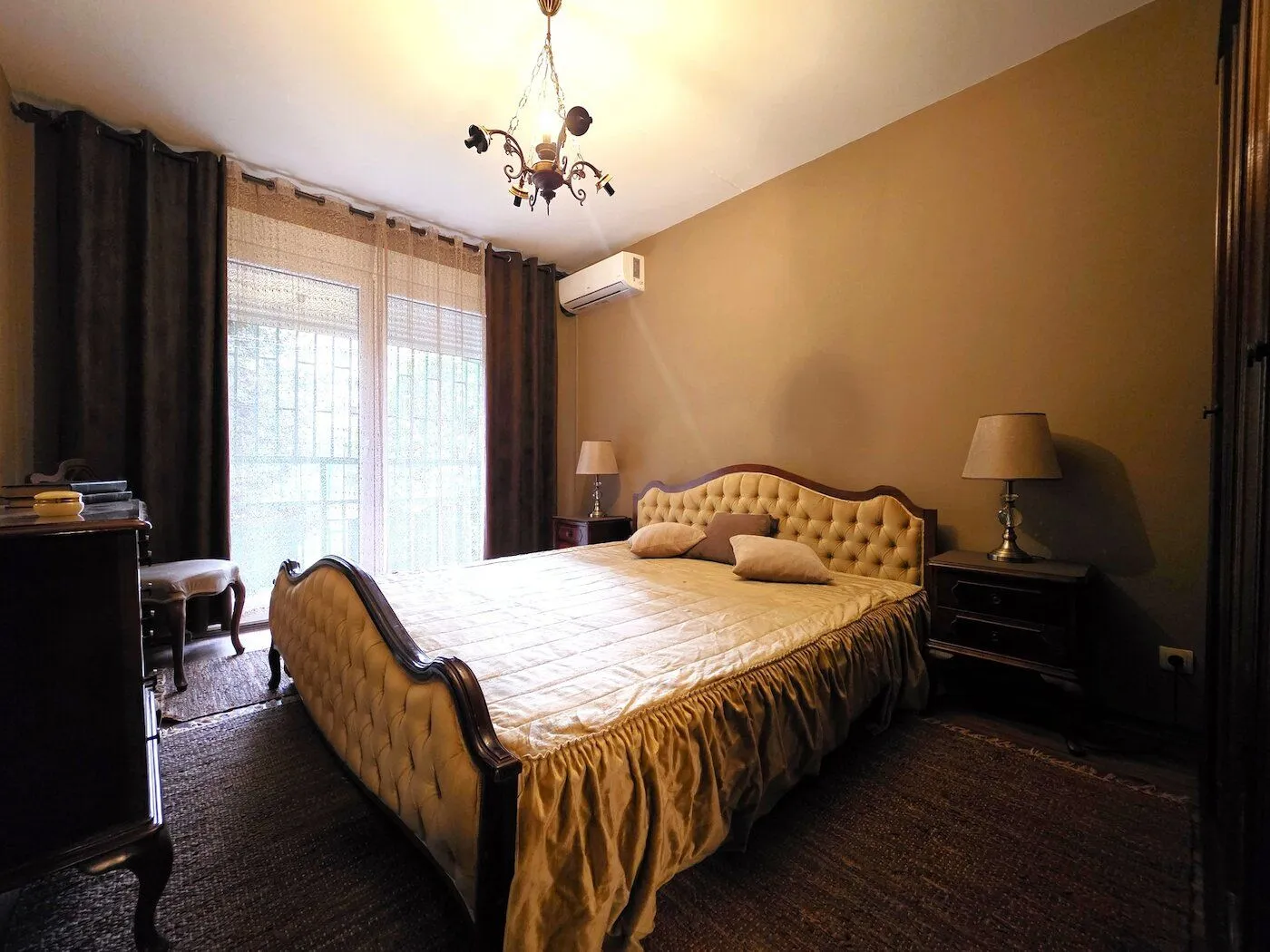 Spacious bedroom with a double bed, bedside tables, and a window with dark curtains.