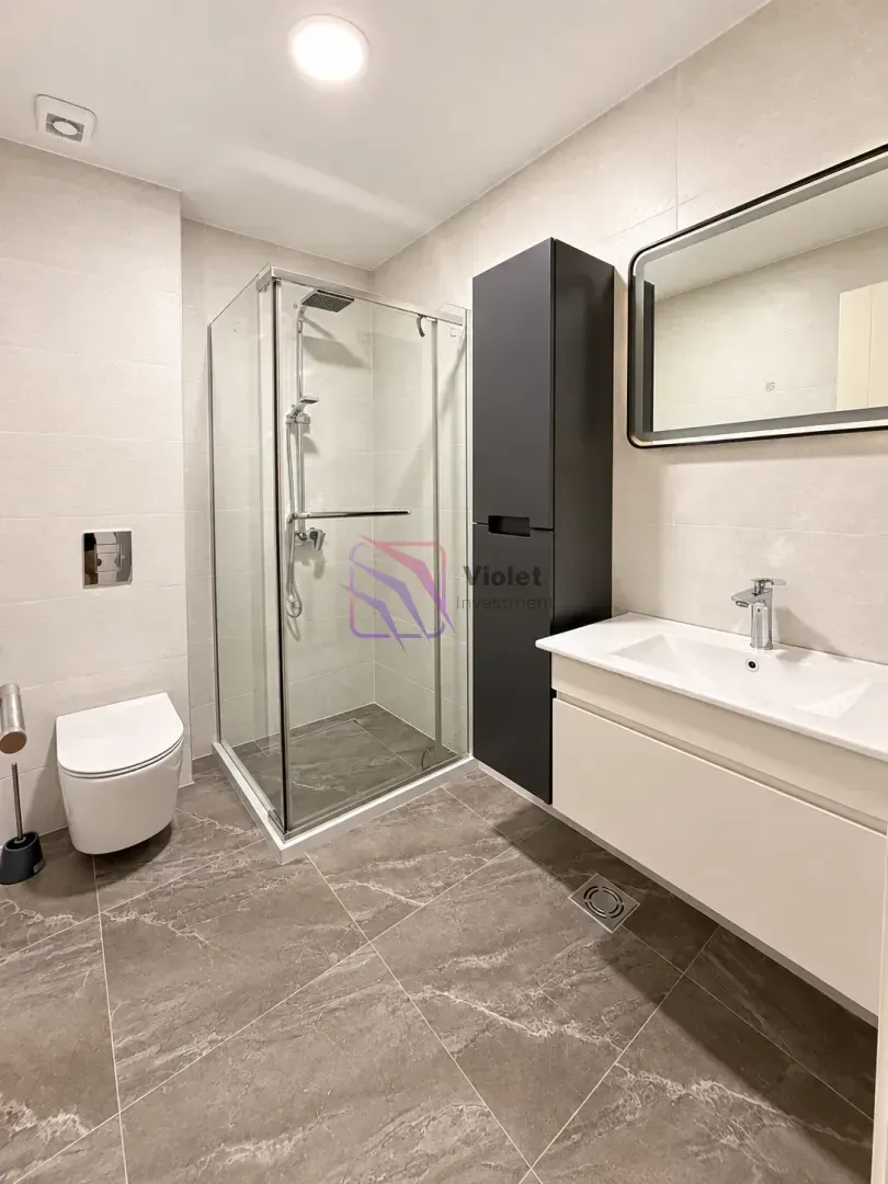 Moderno opremljeno kupatilo sa tuš kabinom, umivaonikom i wc šoljom.