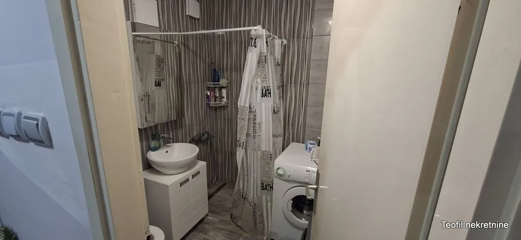 Manje kupatilo sa umivaonikom, tuš kabinom i veš mašinom.