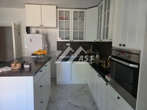 White kitchen with an island and built-in appliances. - image 3
