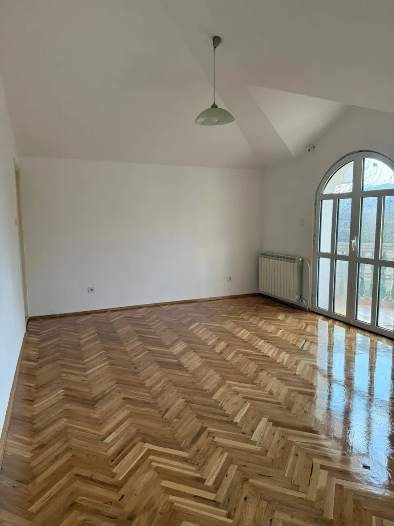 Empty room with parquet flooring and arched balcony doors.