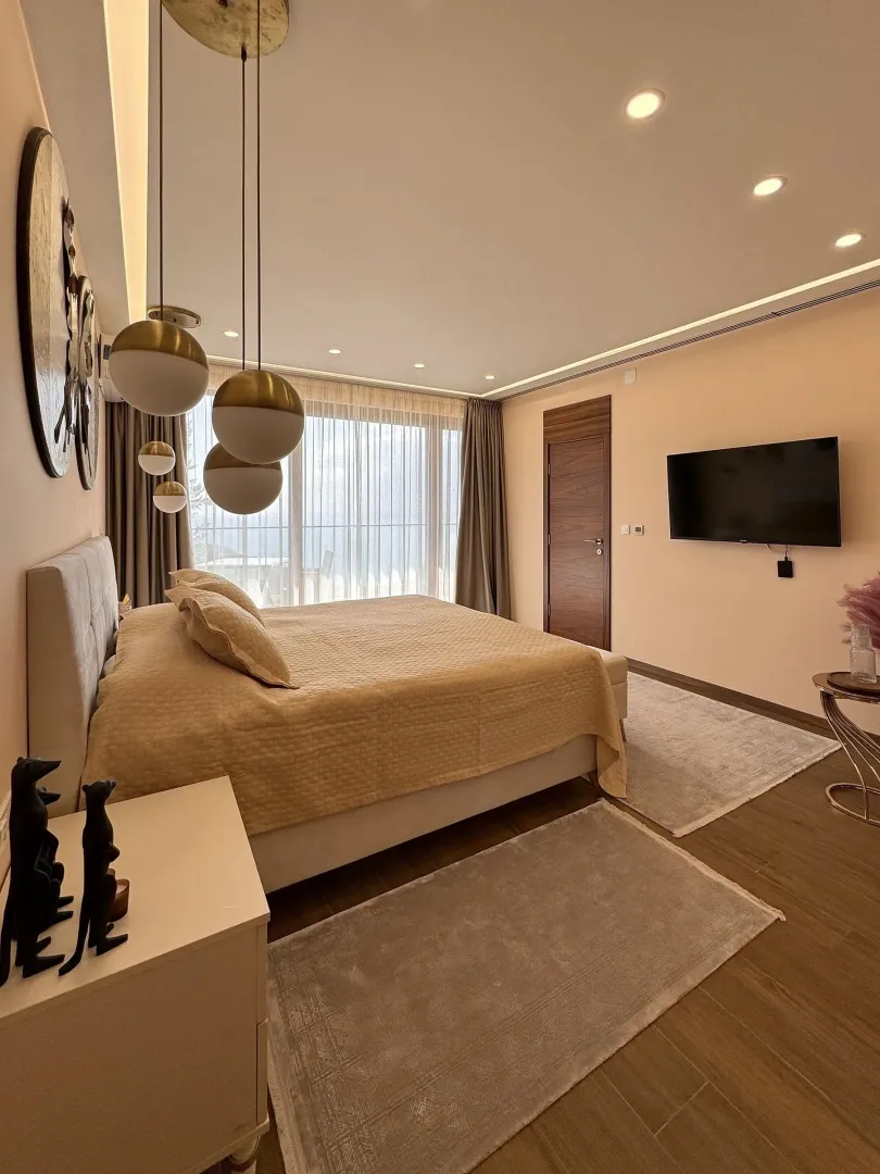 Modern bedroom with a double bed, pendant lights and a wall-mounted TV.
