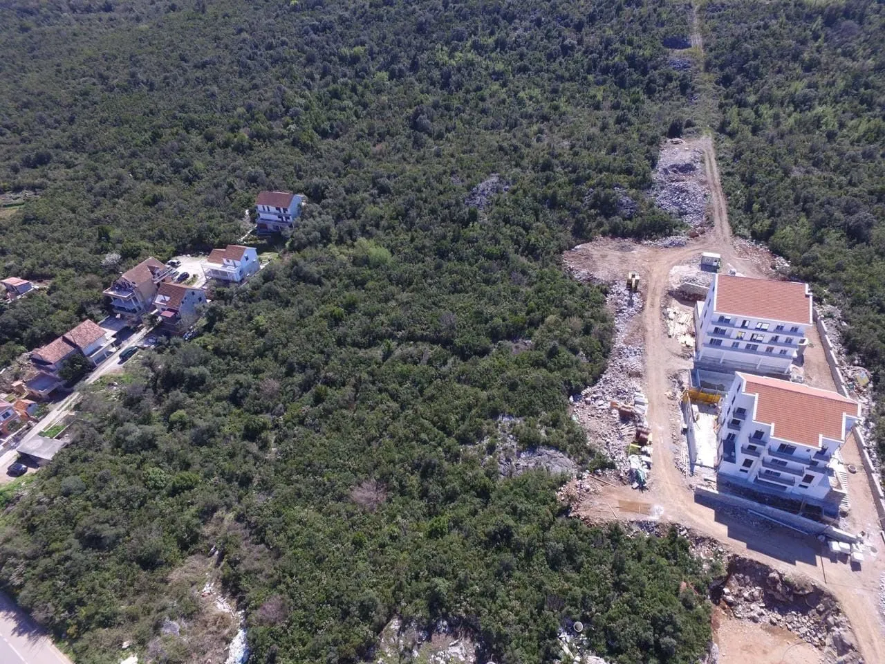 Pogled iz vazduha na naselje i objekte u izgradnji okružene zelenilom.