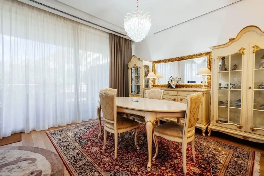 Prostrana trpezarija sa klasičnim namještajem, velikim ogledalom i elegantnim lusterom.