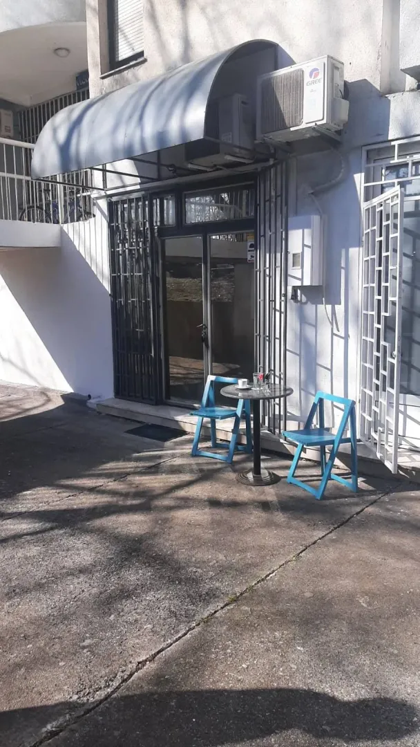 Building entrance with a small table and blue chairs in front.
