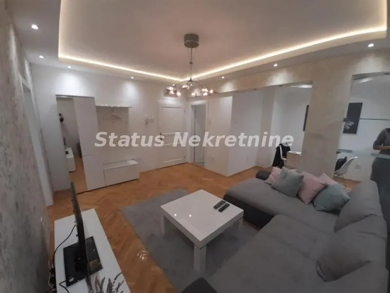 Dnevna soba sa ugaonom garniturom, stočićem i TV komodom.