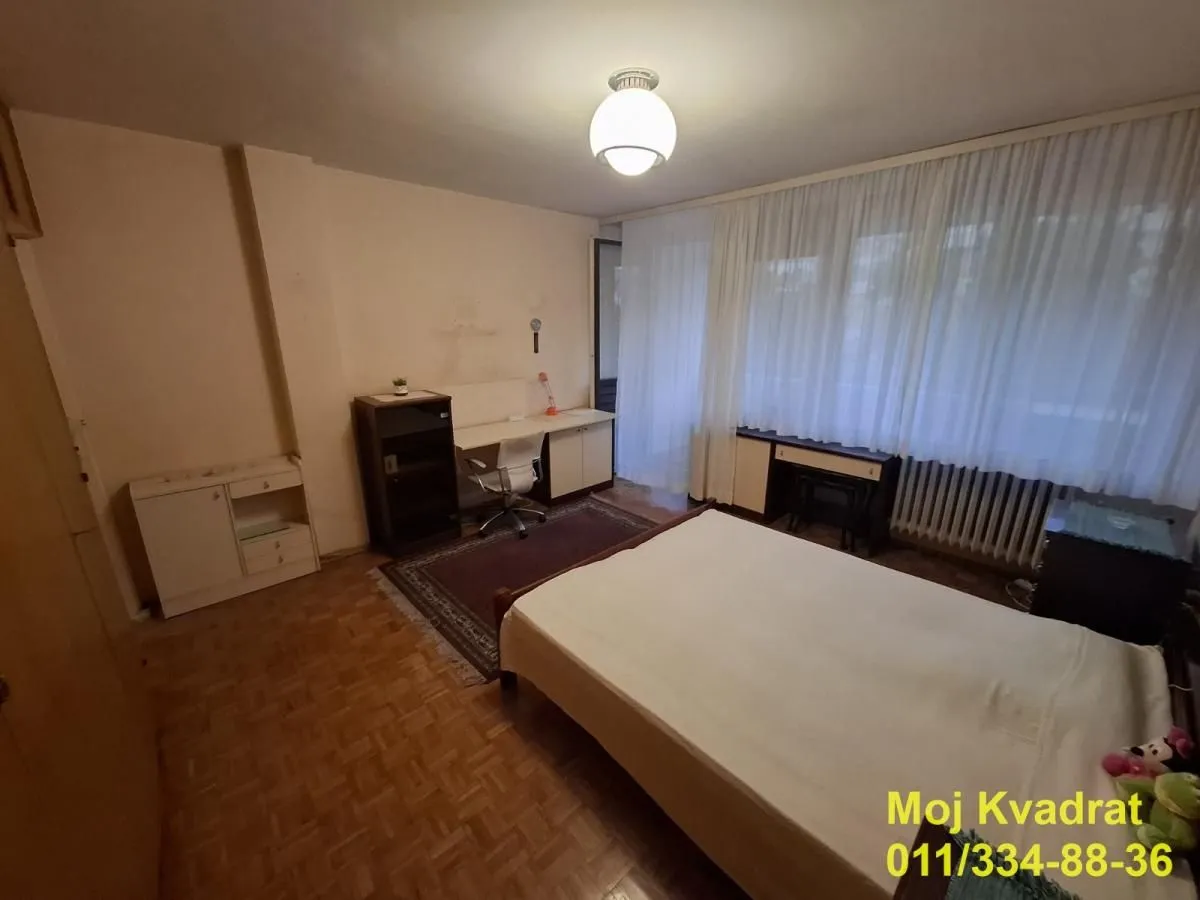Nameštena spavaća soba sa krevetom i radnim stolom.