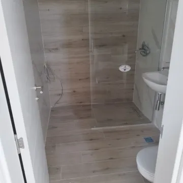 Moderno opremljeno kupatilo sa tuš kabinom i drvenim pločicama. - image 14