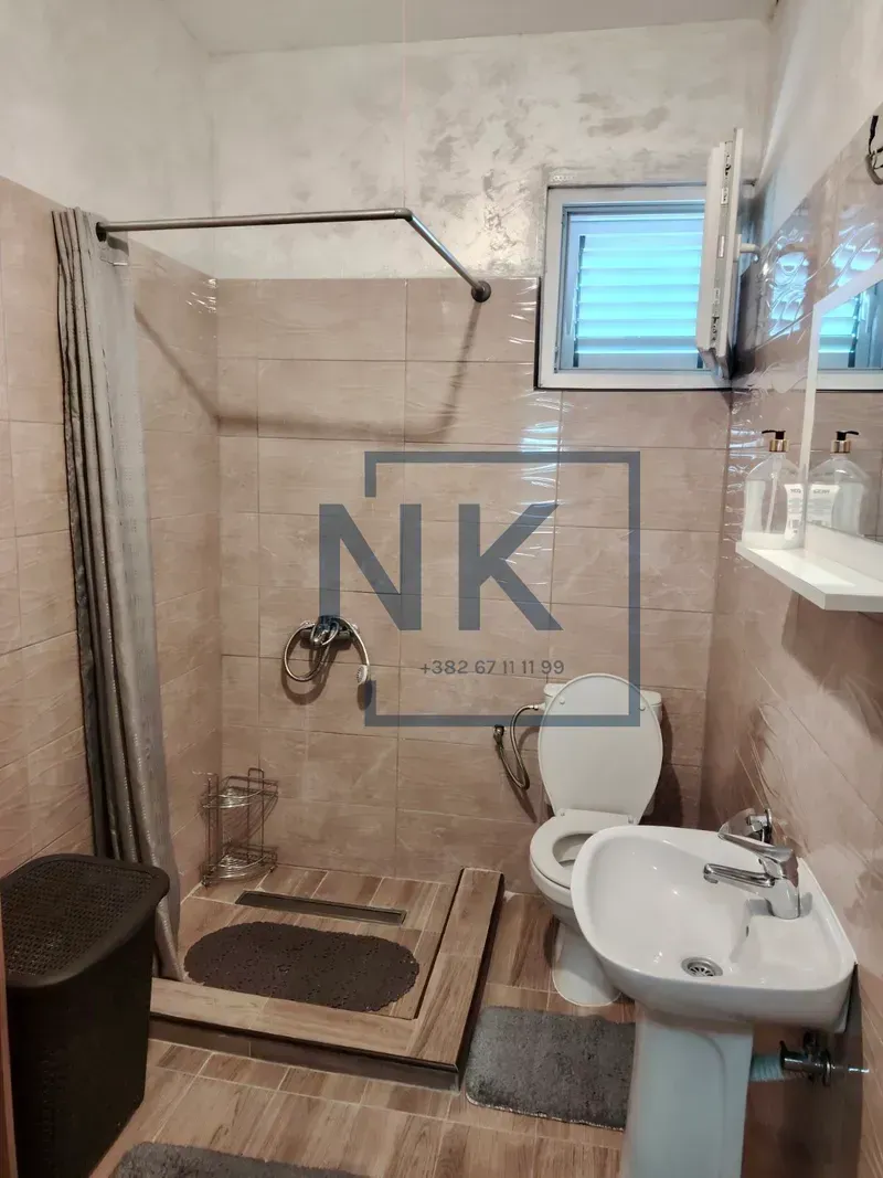 Compact equipped bathroom with a walk-in shower, washbasin, and toilet.