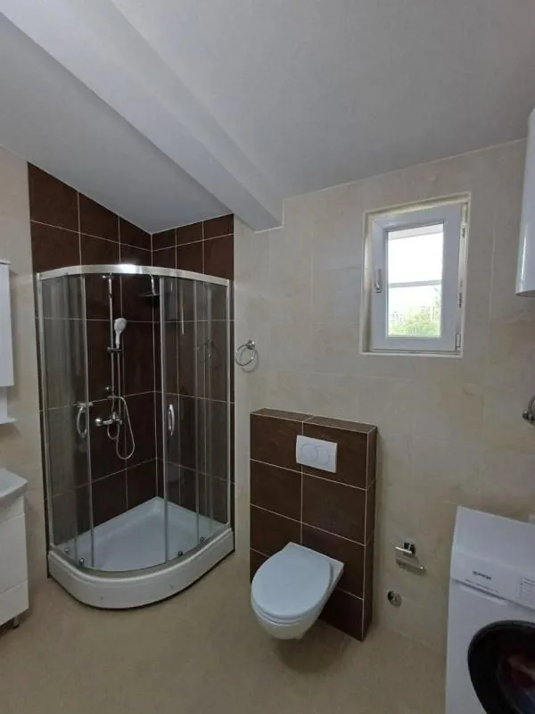 Bathroom with a shower cabin, toilet, and a window.