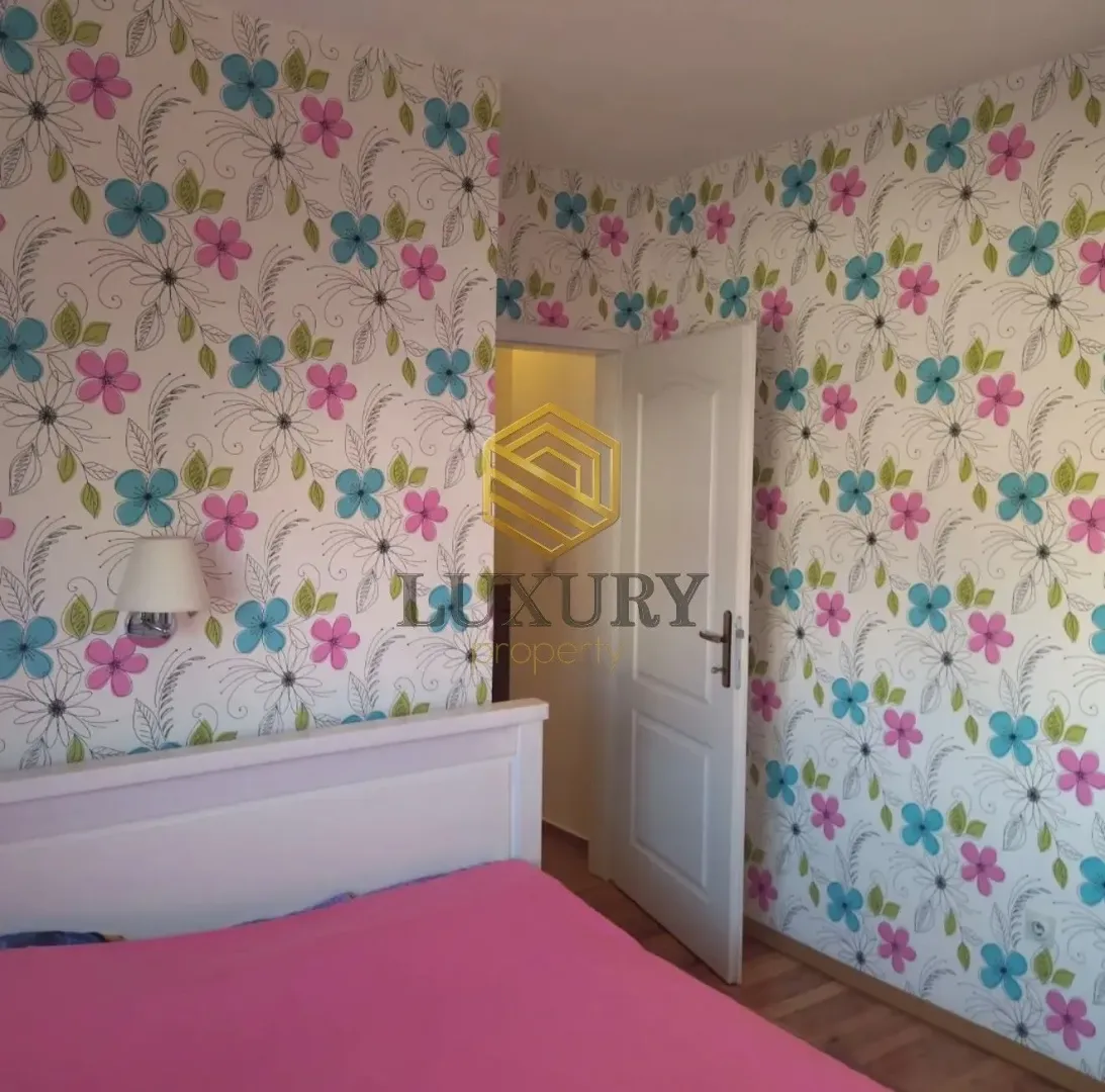 Bedroom with a bed and floral wallpaper on the walls.