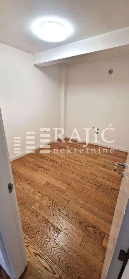 Empty room with wooden flooring and white walls.