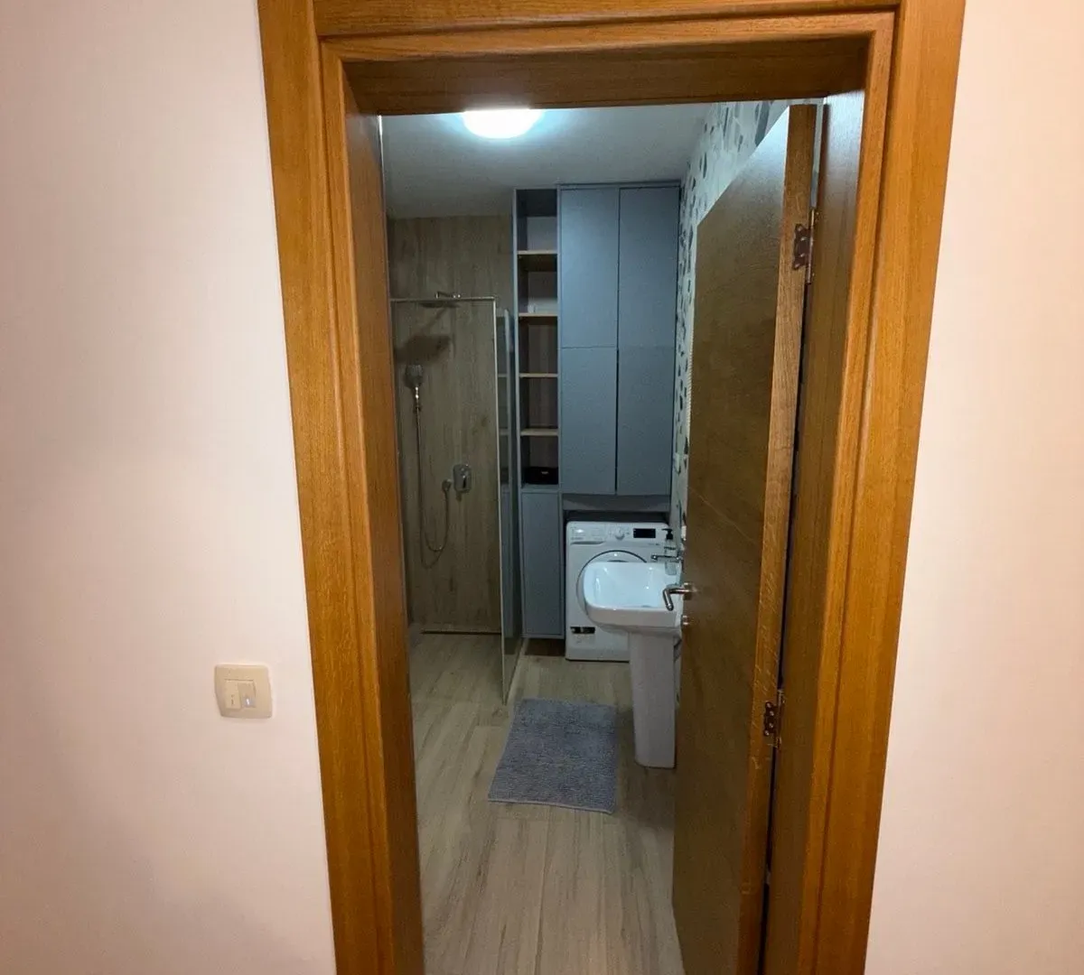 View through the doorway into a furnished bathroom with a shower cabin and washing machine.