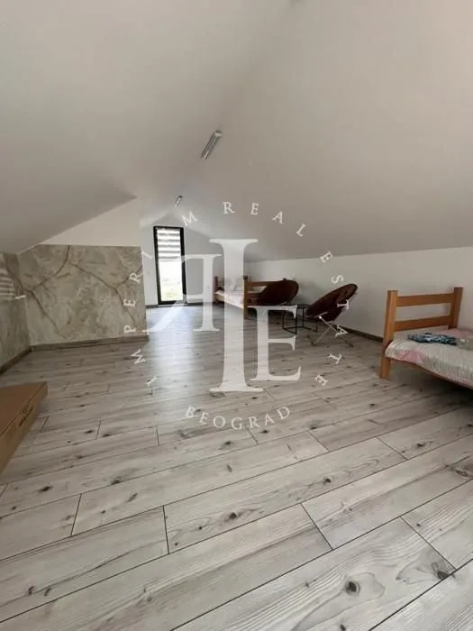 Spacious attic room with wooden beds and laminate flooring.