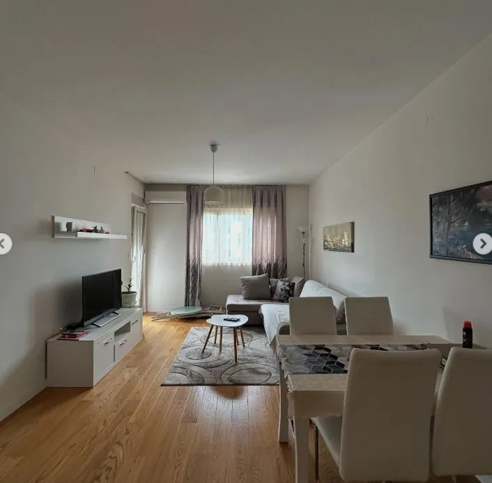 Living room with a sofa, TV console, and dining table.