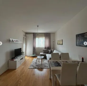 Living room with a sofa, TV console, and dining table. - image 3