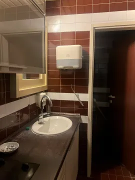 Small bathroom with a sink, mirror, and brown and white wall tiles. - image 8
