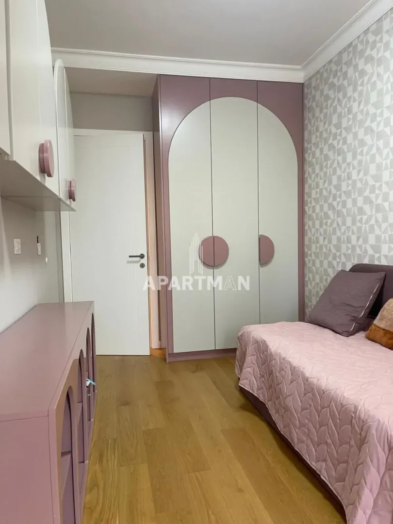 Dečja soba sa krevetom, velikim garderoberom i roze elementima.
