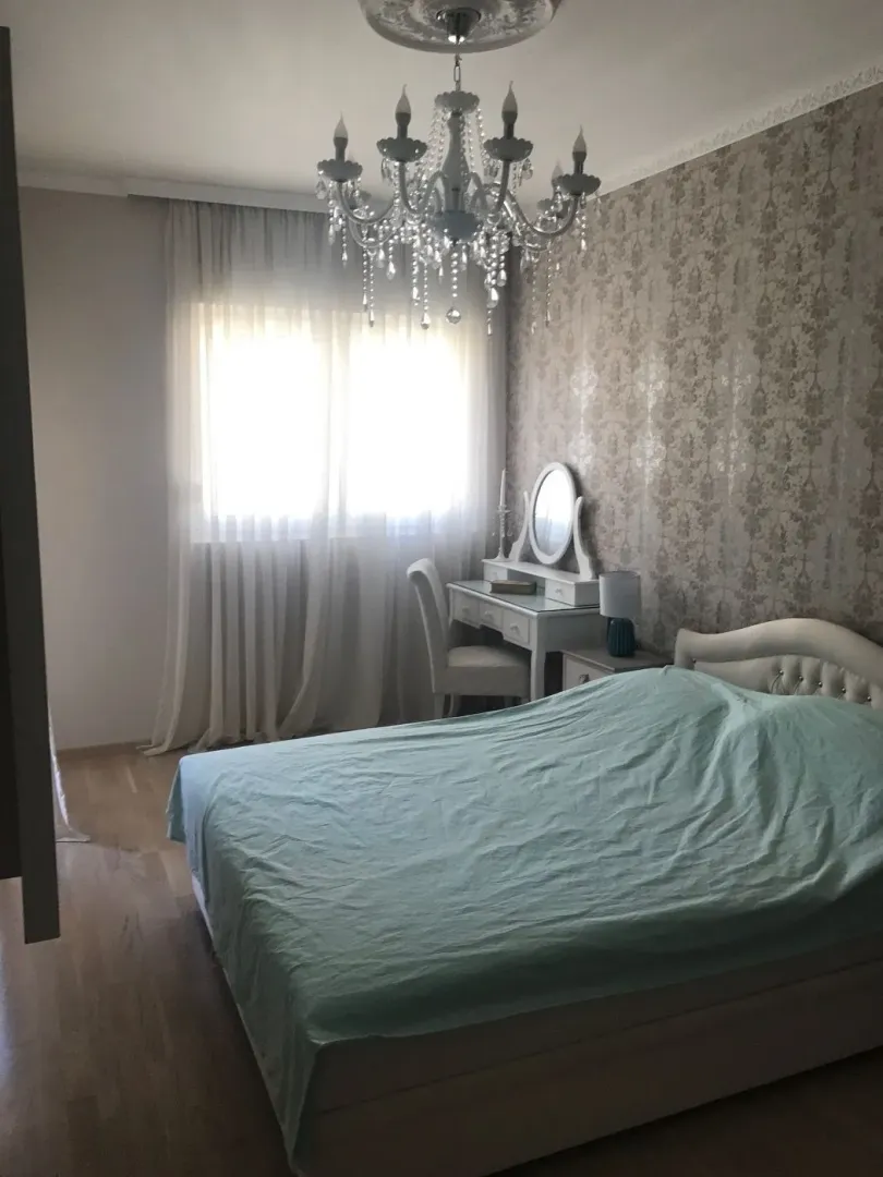 Svijetla spavaća soba sa toaletnim stolom i velikim krevetom.