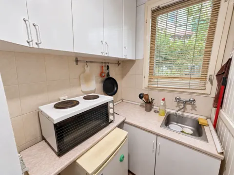 Small kitchen with a sink, stove, and upper cabinets. - image 8
