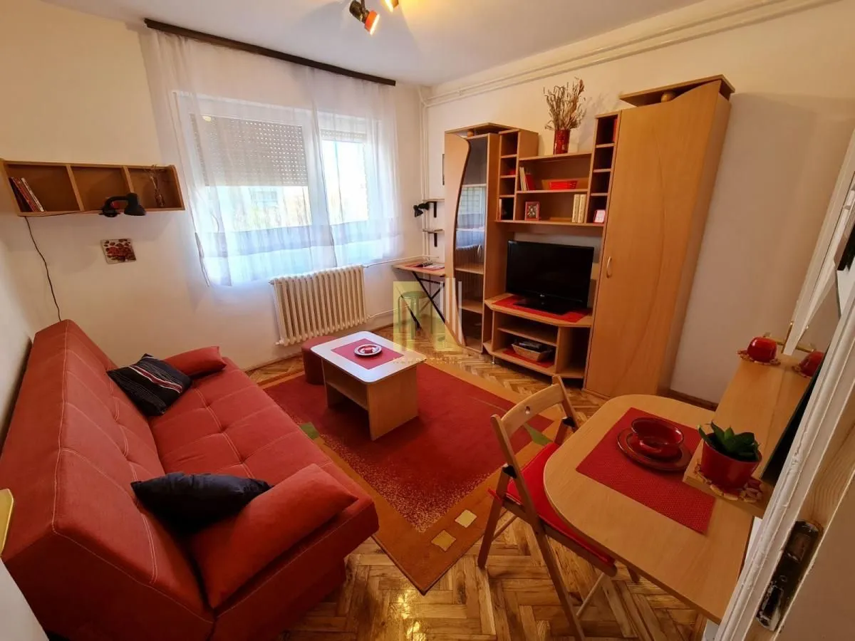 Manja dnevna soba sa garniturom za sedenje, TV policom i radnim stolom.