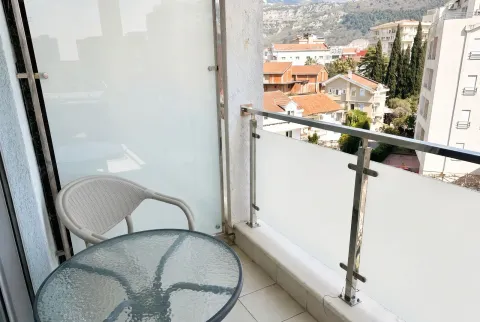 Manji svijetli balkon sa garniturom za sjedenje i pogledom na naselje. - image 4