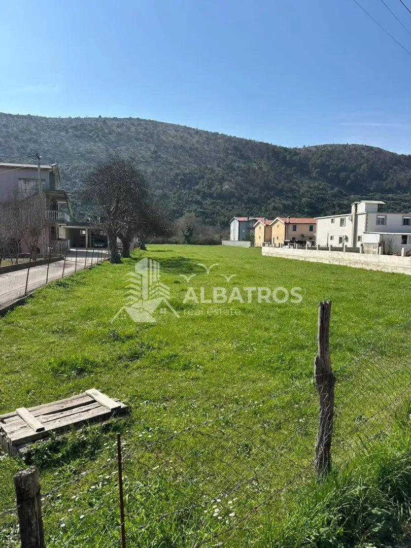 Pogled na prostrano građevinsko zemljište sa travnatom površinom i okolnim kućama.