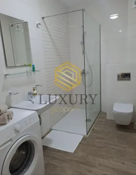Modern bathroom with a walk-in shower, washbasin, toilet, and washing machine. - image 8