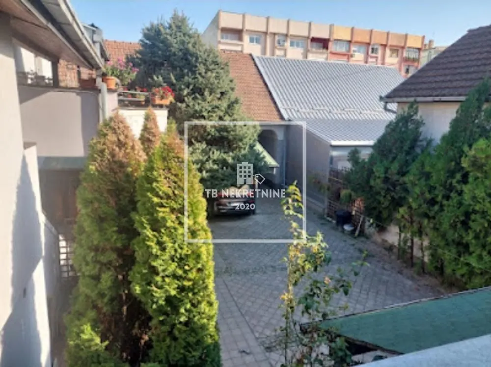 Pogled na dvorište i okolne objekte sa zelenilom.