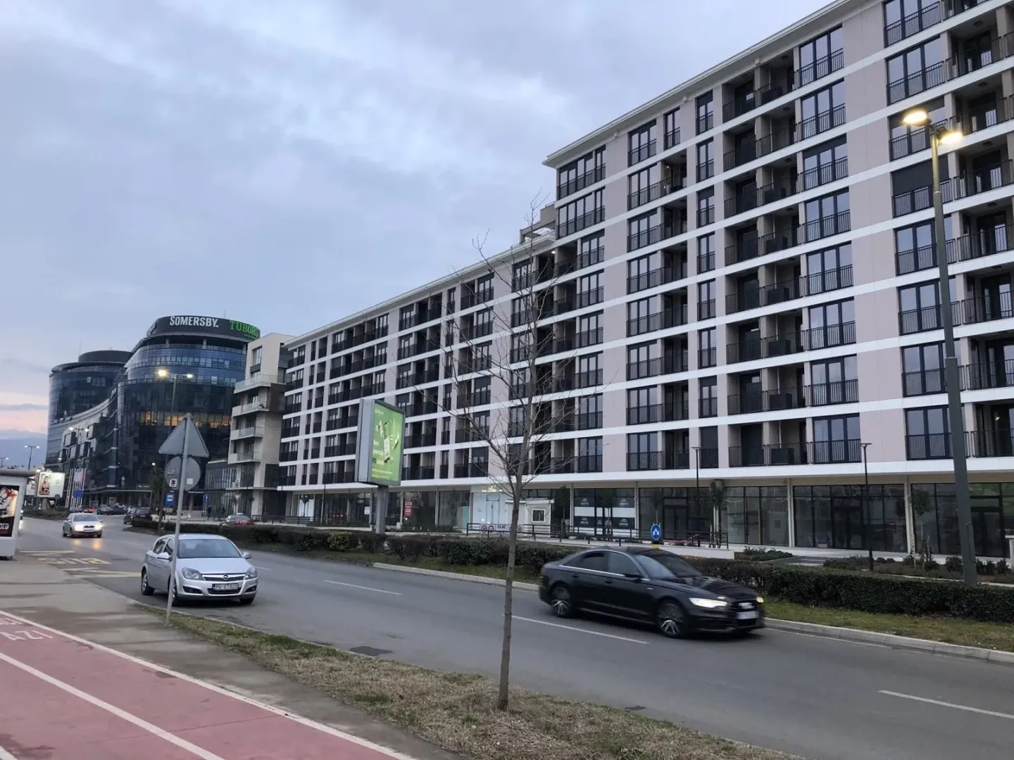 Eksterijer moderne stambene zgrade pored ulice sa automobilima.