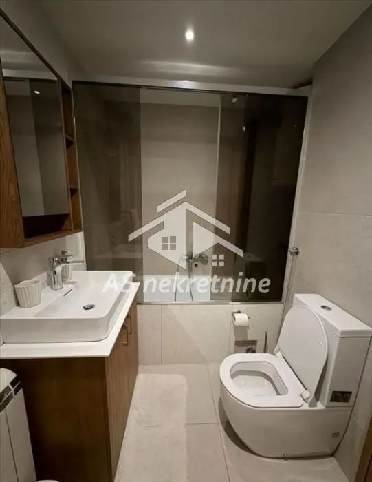 Modern bathroom with a washbasin, toilet, and glass shower cabin.