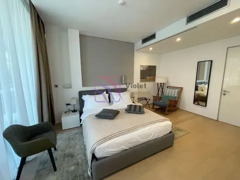 Moderna spavaća soba sa bračnim krevetom, foteljom i velikim prozorom.