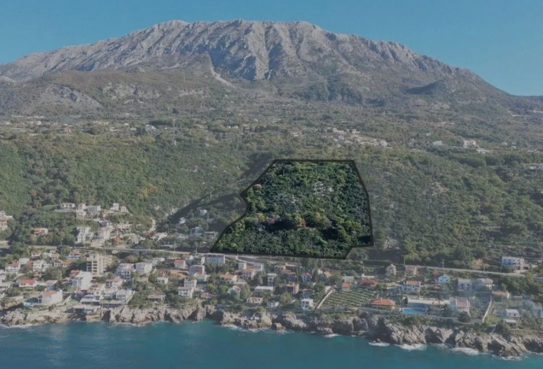 Vazdušni snimak terena sa označenom granicom parcele i pogledom na planinu i more.