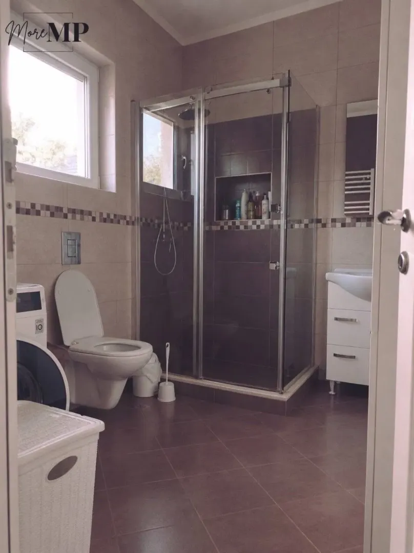 Kupatilo opremljeno tuš kabinom, WC šoljom i umivaonikom sa ormarićem.