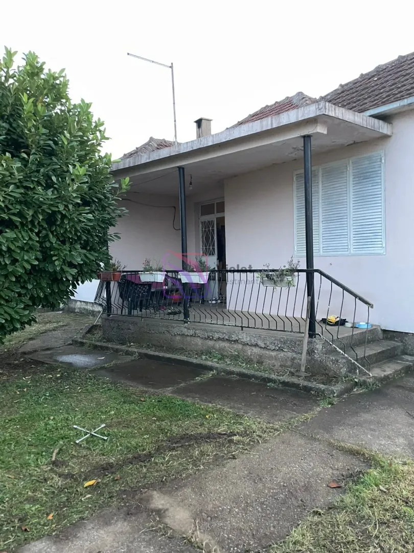 Pogled na spoljašnjost kuće sa natkrivenom terasom i dvorištem.