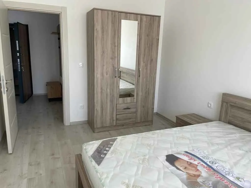 Jednostavna spavaća soba sa drvenim ormarom i krevetom.