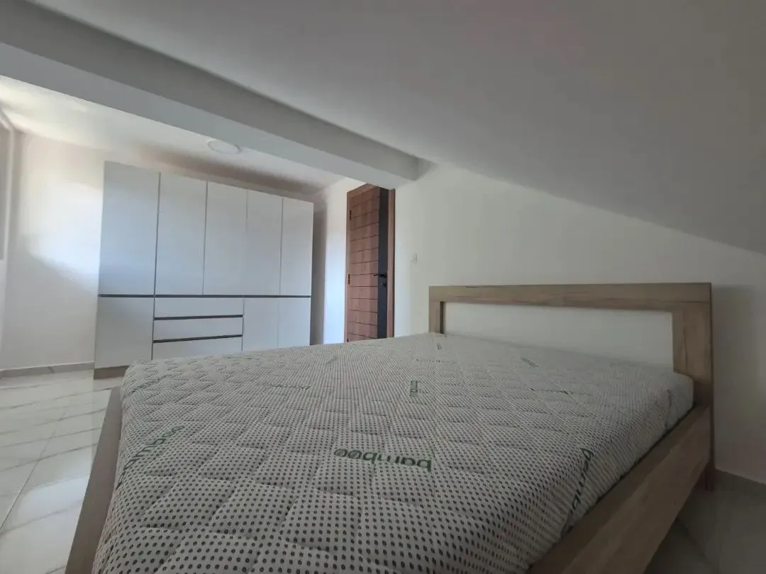 Spavaća soba sa bračnim krevetom i ugradnim plakarom pod kosim krovom.