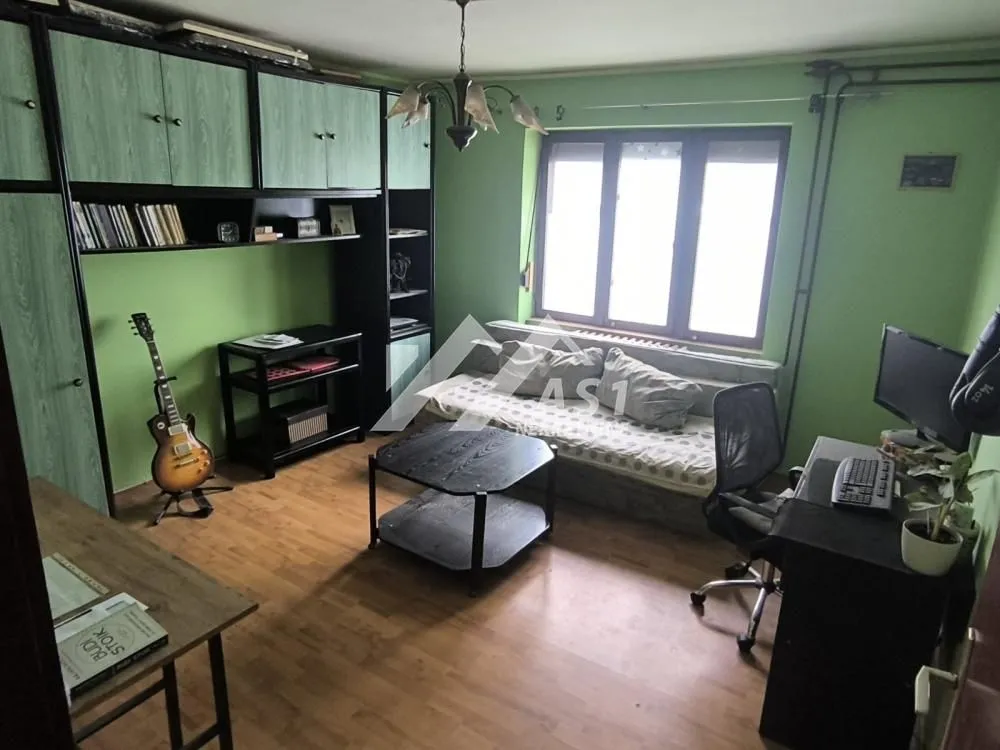 Furnished living room with a desk and green walls.