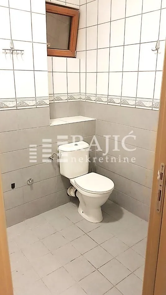 Manje kupatilo sa WC šoljom i keramičkim pločicama na zidovima.