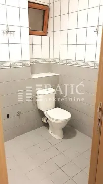 Manje kupatilo sa WC šoljom i keramičkim pločicama na zidovima. - image 18
