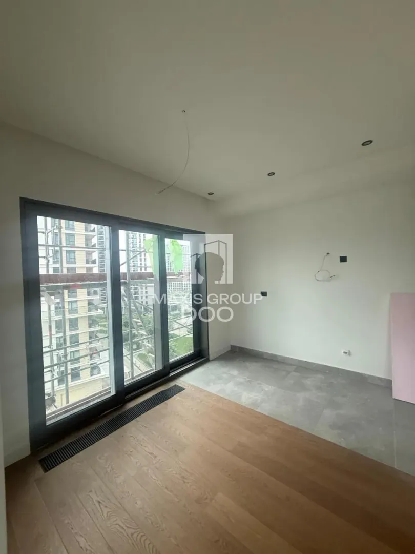 Unfurnished room under construction with parquet flooring and a large window.