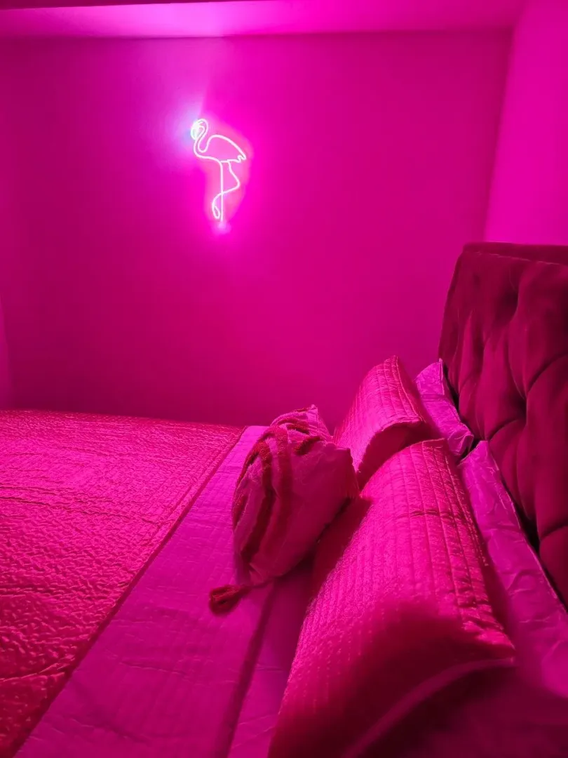 Modern bedroom illuminated by pink neon light.